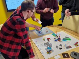People leaning in to talk about their models during a LEGO SERIOUS PLAY workshop