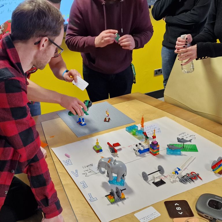 People leaning in to discuss their LEGO models in a workshop